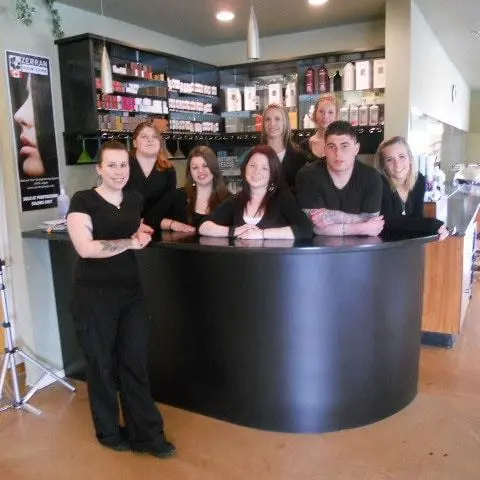 Several people positioned behind a salon counter, interacting with customers and showcasing a welcoming atmosphere.